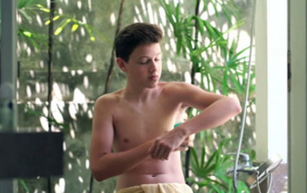 A boy applies deodorant under his arms
