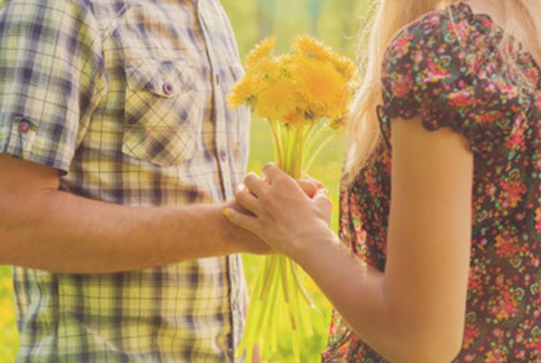 A guy gives a girl yellow dandelions